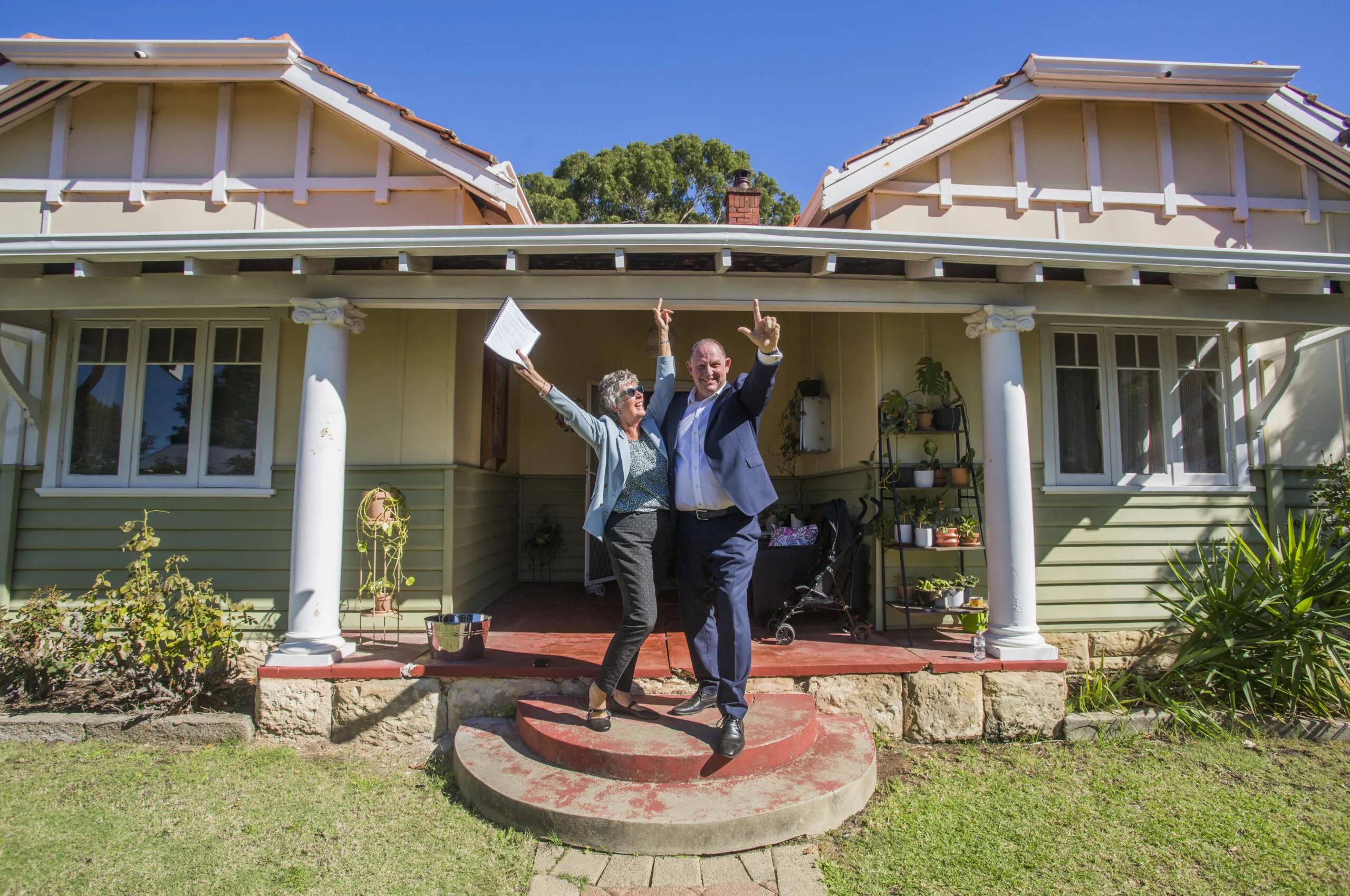 A photo of Amanda Kerr standing in front of a house that she just sold.